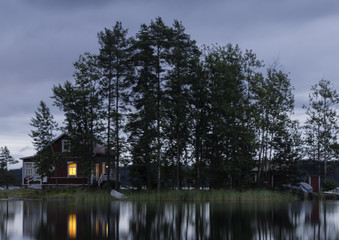 Obraz premium The island in the lake at sunset. The sky in the clouds. The smooth surface of the water.