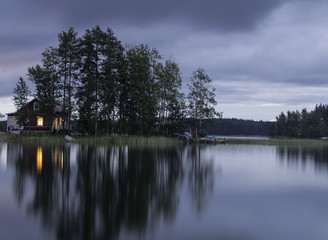 The island in the lake at sunset. The sky in the clouds. The smooth surface of the water.