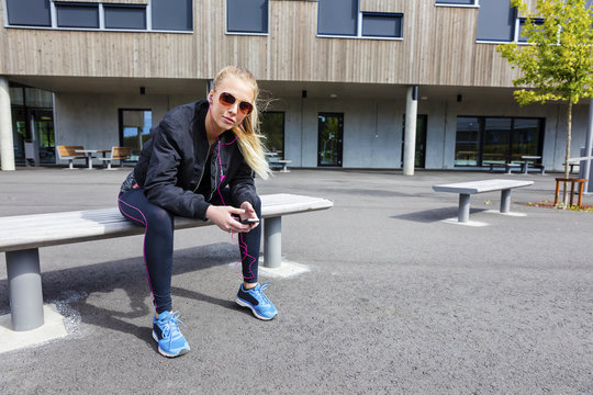 Urban female in workout outfit uses phone outdoor