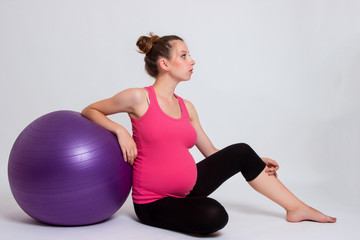 Fototapeta na wymiar pregnant woman practicing yoga on a light background