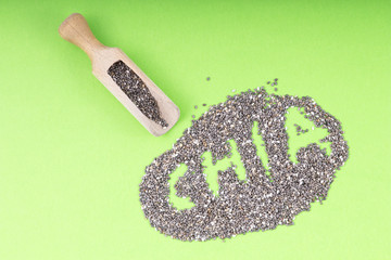 Chia seeds. Chia word made from chia seeds with wooden spoon on green background.