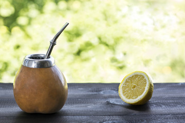 yerba mate in gourd matero with half of lemon on wooden table