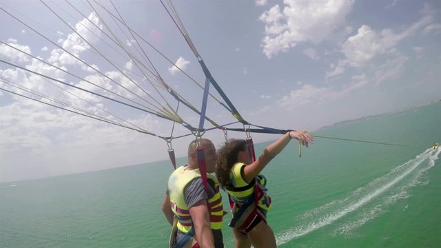 Happy man and girl fly on glider over sea at sunny summer day