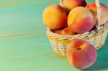 Peaches in basket on wooden background