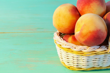 Peaches in basket on wooden background
