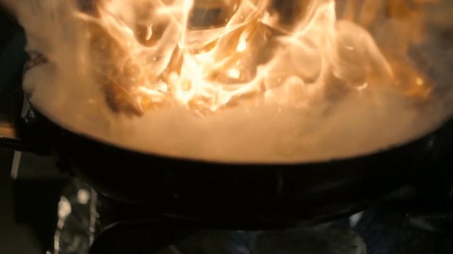 Chef Cooking With Fire In Frying Pan.
Professional Chef In a Commercial Kitchen Cooking Flambe Style. Cooking Beef Stroganoff.
