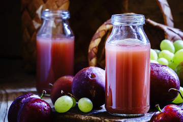 Juice, nectar of sweet plums and grapes in glass bottles, vintag