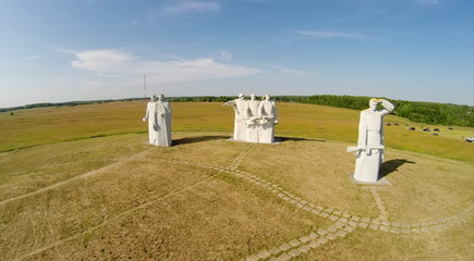 People stand near monument of 28 Heroes Panfilovtsev on field. Aerial view. (Photo with noise from action camera)