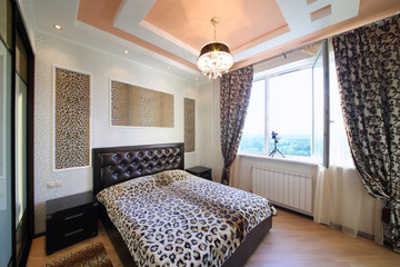 Interior modern bedroom in the Greek style with leopard print on the walls and bed