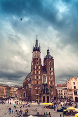 Fototapeta na wymiar Church of St. Mary in the main Market Square in cloudy weather. Basilica Mariacka. Dramatic sky. Krakow. Poland.