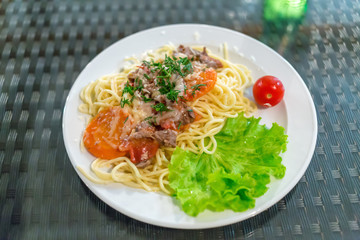 plate of pasta with meat, vegetables and lettuce