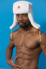 young sportive African in white fur hat with a red star on blue background - obrazy, fototapety, plakaty