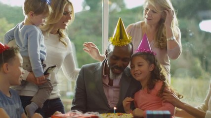  Mature man celebrates his birthday with a cake & happy family group