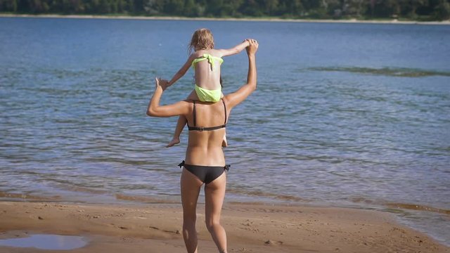 Mother carrying on shoulders her little daughter