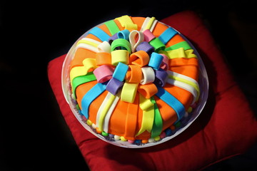 Beautiful varicolored birthday cake with imitation ribbons.
