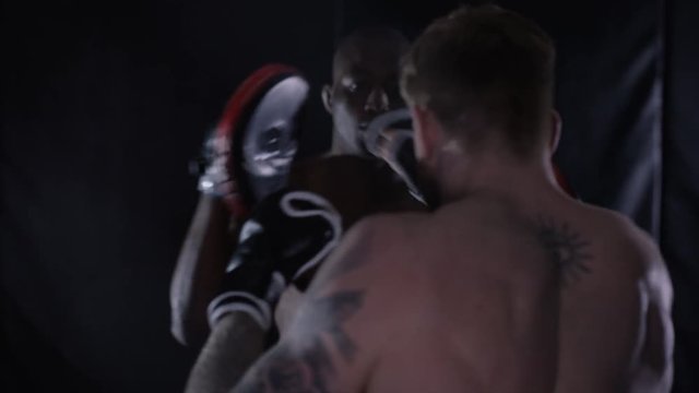  Muscular MMA fighter training with partner in dark environment