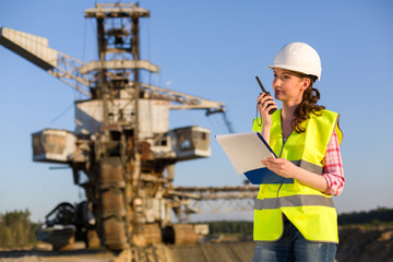 female worker talking on a radio on a background of career Stacker