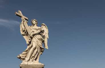 A large, stone statue of an angel, against a deep blue summer sky - obrazy, fototapety, plakaty
