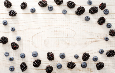 Fototapeta na wymiar Oval frame with blueberries and blackberries on a light wooden background