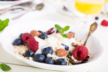Healthy breakfast. Oat flakes with fresh berries , yogurt and honey on white table.