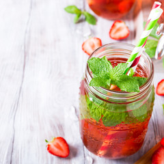 Homemade delicious strawberry compote in glass jar on white wooden table. Healthy food concept with copy space.