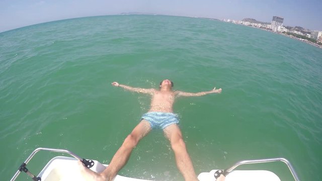 Teen boy lying on sea water surface refreshing