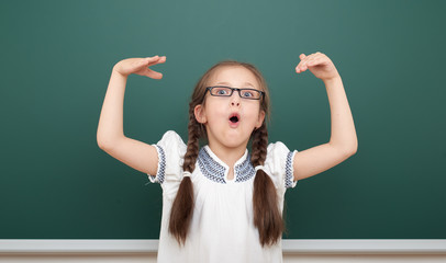 school student girl open arms at the clean blackboard, grimacing and emotions, dressed in a black...