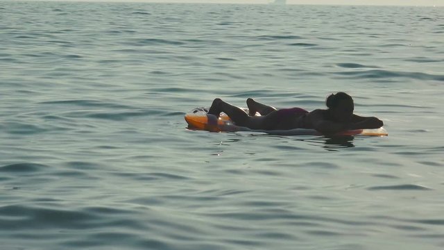  Fit girl relaxing on lilo on a sea sunset 