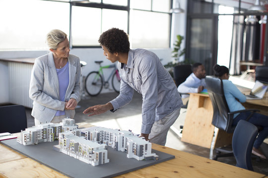 Architects discussing over architectural model in office