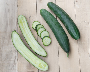 Fresh and ripped cucumbers decorated with rosemary on wooden des