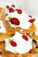 waffles with wild strawberries and whipped cream on white table