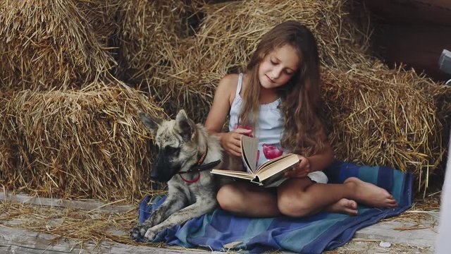 Young Curly Girl Reads a Book With His Dog