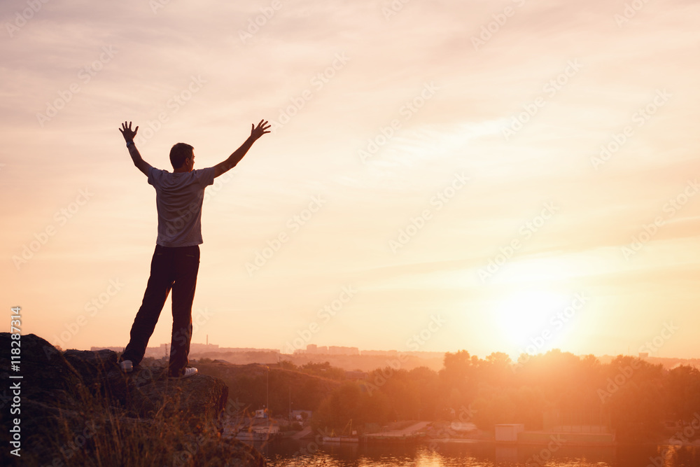 Wall mural silhouette of a man with raised-up arms at the beautiful sunset on the mountain. background
