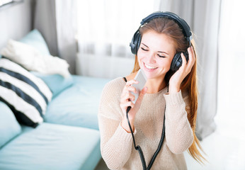 Woman with headphones singing and listening to music at home