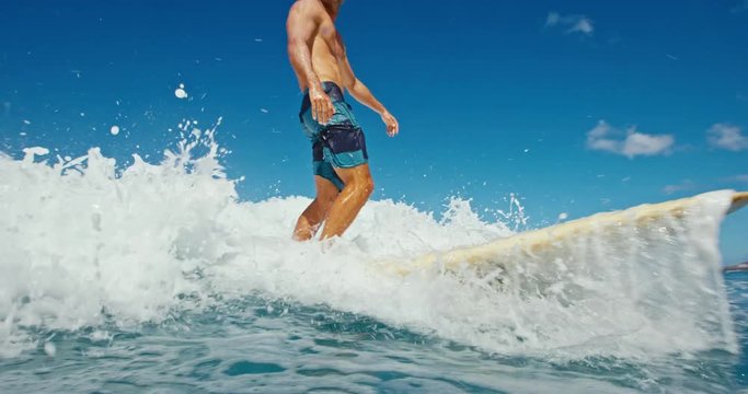 Young man having fun surfing, riding ocean wave in slow motion