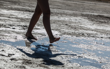 legs girl walking on the salt lake with her shadow