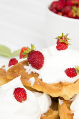 waffles with wild strawberries and whipped cream on white table