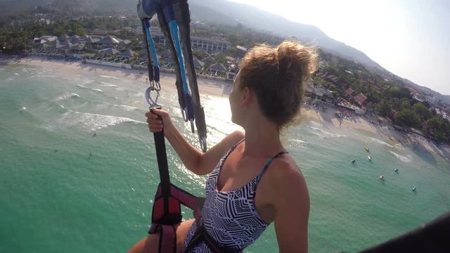 Parasailing Girl Flying with GoPro in Sky Against Tropical Beach