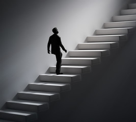 Man walking up the stairs towards light