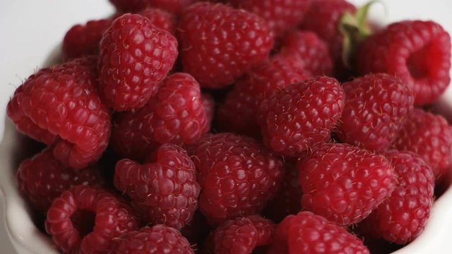 Fresh raspberry rotation in white bowl. Top view, closeup