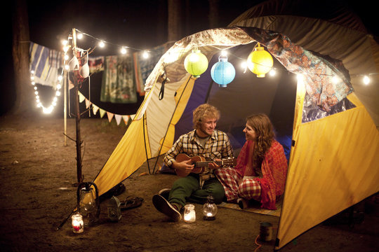 Couple Playing Music In Camping Tent At Night