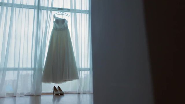 White wedding dress hanging in front of the window