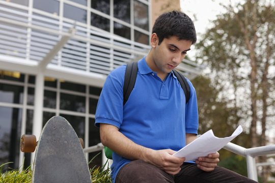 Middle Eastern student reading notes on campus - Powered by Adobe