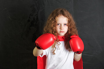 Little girl in red boxing gloves showing aggressive face express
