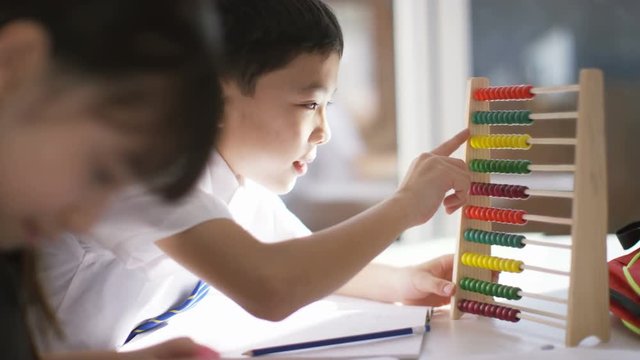  Young school children in class with little boy using an abacus