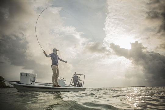Caucasian fisherman casting line from boat