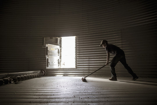 Teenage boy sweeping empty silo
