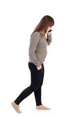 Fototapeta premium side view of a woman walking with a mobile phone. back view of girl in motion. backside view of person. Rear view people collection. Isolated over white background. with his hand in the pocket of a