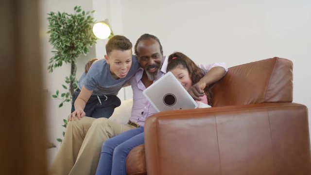  Happy grandfather & grandchildren taking selfie with computer tablet
