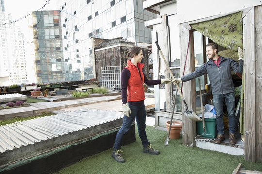 Couple holding gardening tools on urban rooftop